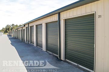 Self storage steel building tan with green doors and gutters