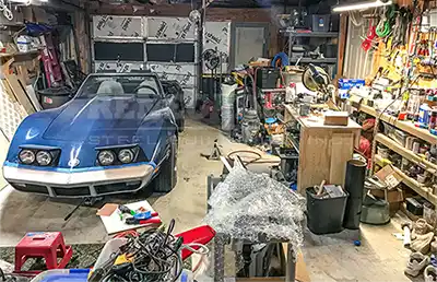 Messy cluttered up garage with Corvette and tools