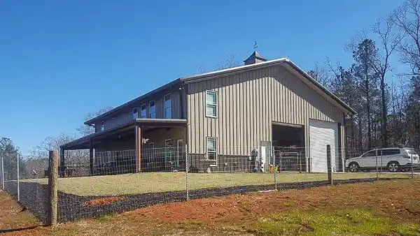 Barndominium building with tan walls and brown wainscot with a lean to porch