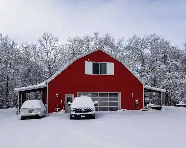 Barndominium with traditional barn shape "Gambrel" roof and 2 lean tos. Red with white trim.